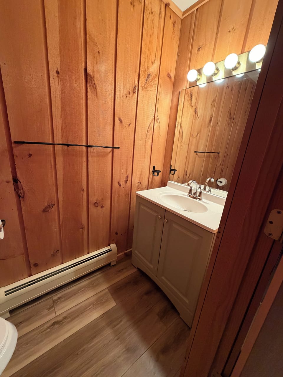 Cozy rustic bathroom with warm wood finishes and bright vanity lighting