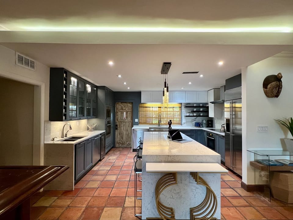 Modern chef’s kitchen with dark cabinetry and a waterfall-edge island.