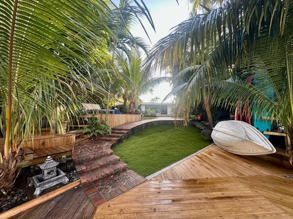 Lush tropical garden with a wooden deck and manicured lawn.