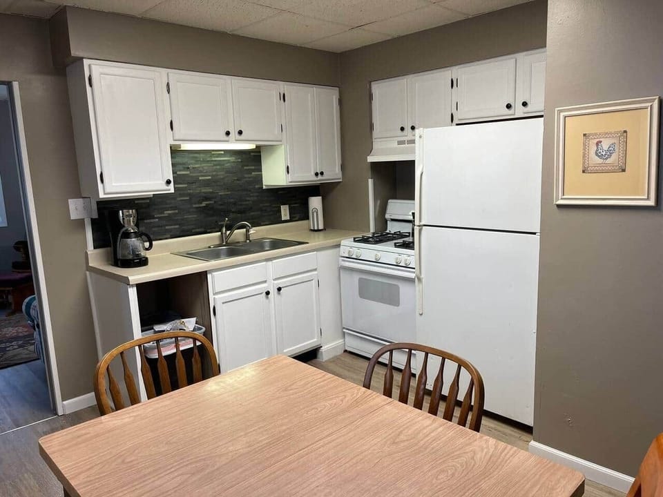 Kitchen with fridge, stove, coffee maker, pots and skillets and utensils. 