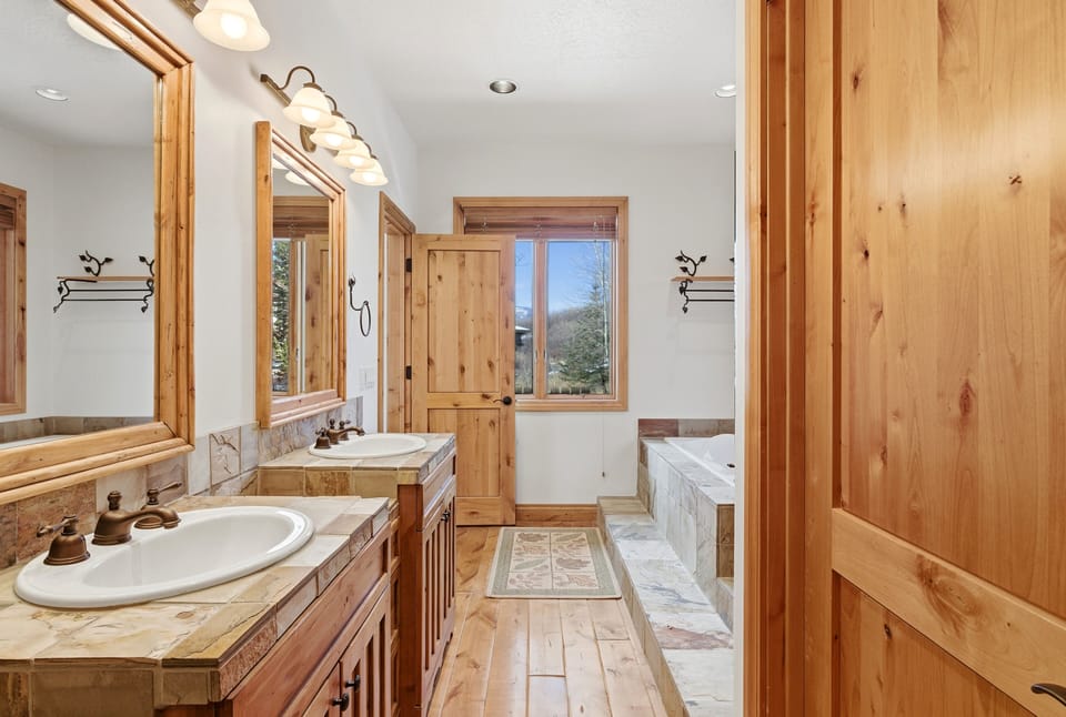 Charming bathroom featuring double vanities with rustic wood cabinetry, wall-mounted lights, and large mirror.
