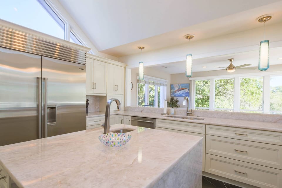 The kitchen features a Subzero refrigerator, a central island, custom cabinetry and quartzite counters.