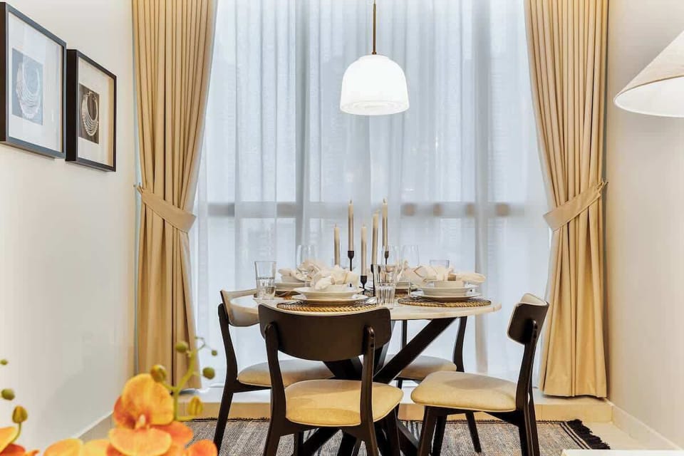 Cozy dining area featuring a comfortable four-seater table next to a large window with stunning lake views, seamlessly connected to the living area for a spacious and inviting layout.