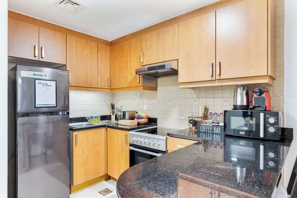 Modern open kitchen fully equipped with an electric induction stove, oven, refrigerator, microwave, coffee machine, utensils, and all essential cookware—perfect for preparing meals in the comfort of your holiday home.