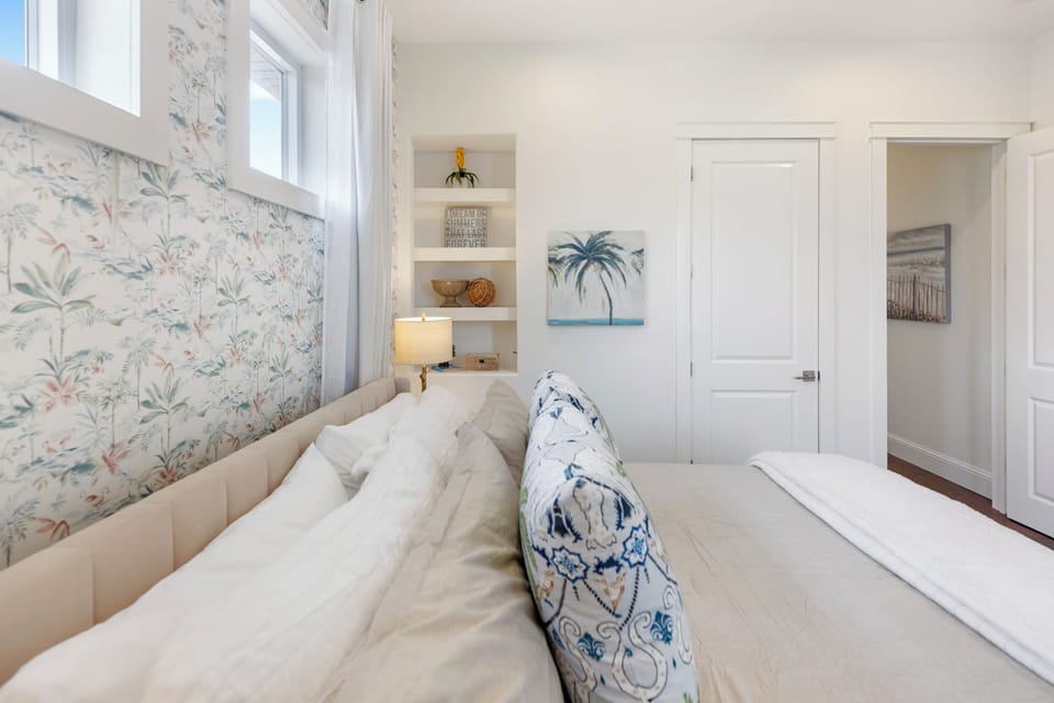 Drift into peaceful sleep in your coastal sanctuary, where tropical wallpaper and built-in shelving create a serene retreat.