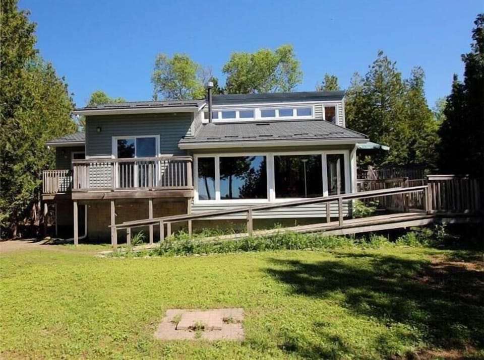 Spacious waterfront cottage with large windows and a sunny yard overlooking the lake.