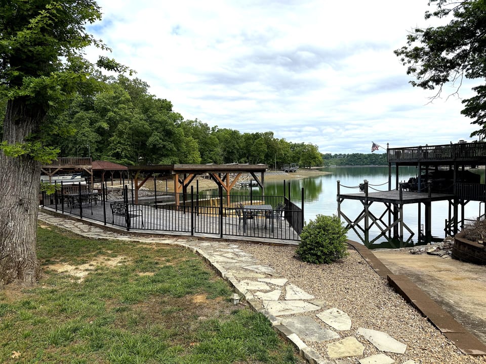Stone walkway leading down to the fenced lakefront dock and patio seating area.