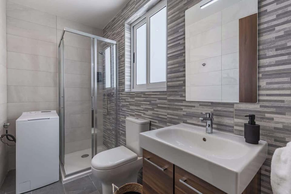 The ensuite bathroom, equipped with a high-pressure shower, comes stocked with plush towels, hand towels, shower gel, shampoo, and conditioner.