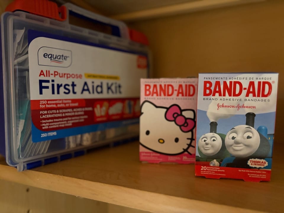 A first aid kit and extra adhesive bandages stored under the coffee station.