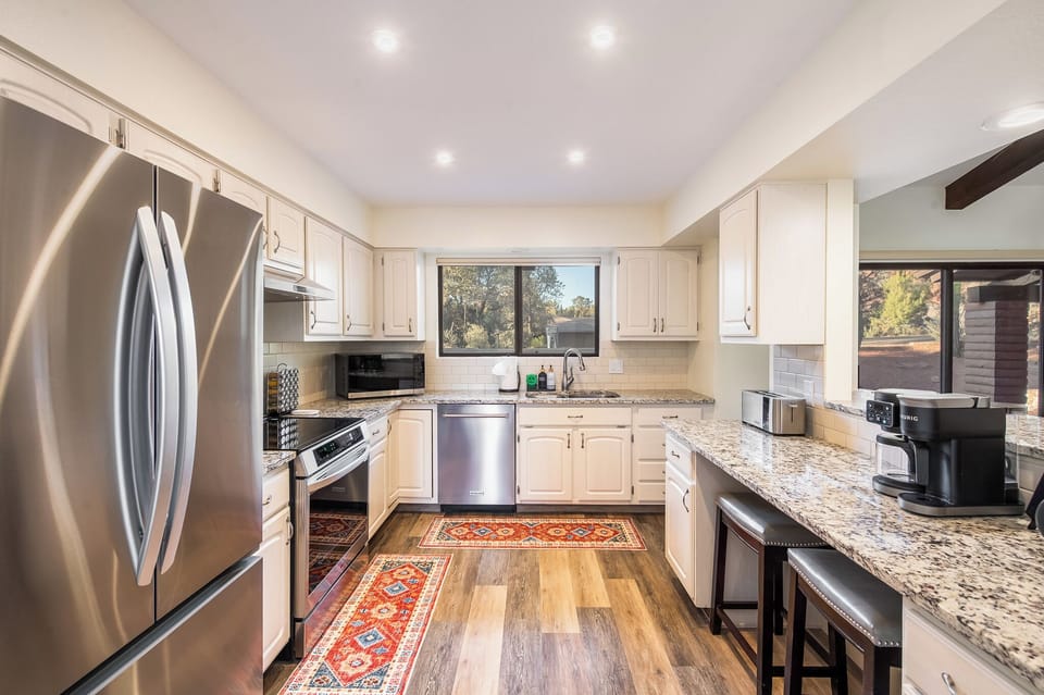 Chef's kitchen with stainless appliances, granite counters, Keurig, and cookware