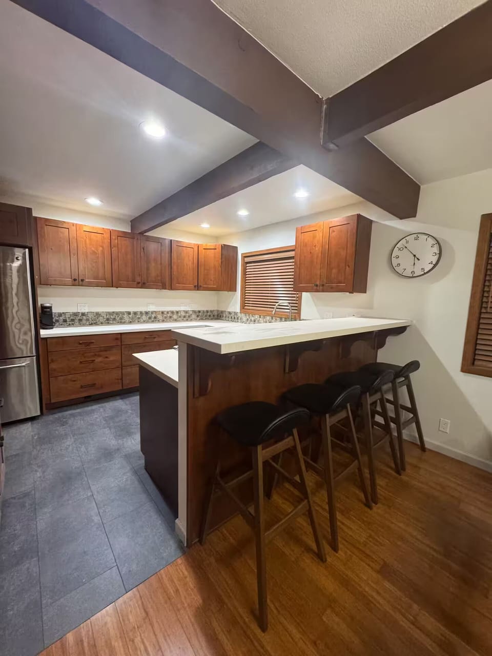 Kitchen has a bar with four extra barstools to sit