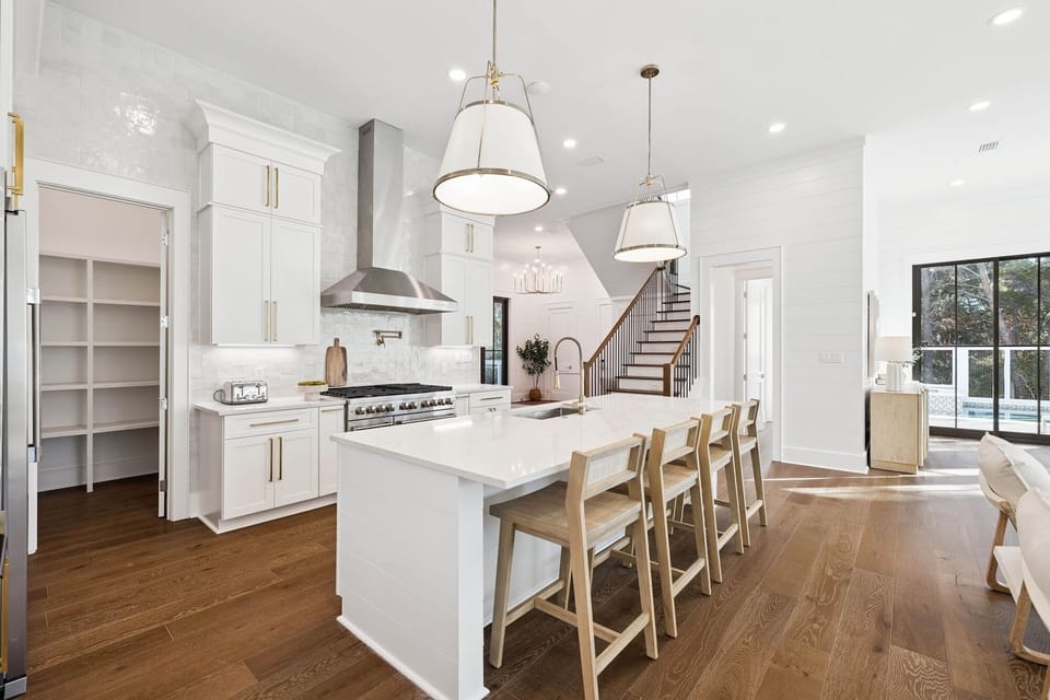 Prepare memorable meals in this pristine white kitchen featuring a spacious island, professional-grade appliances, and elegant pendant lighting.