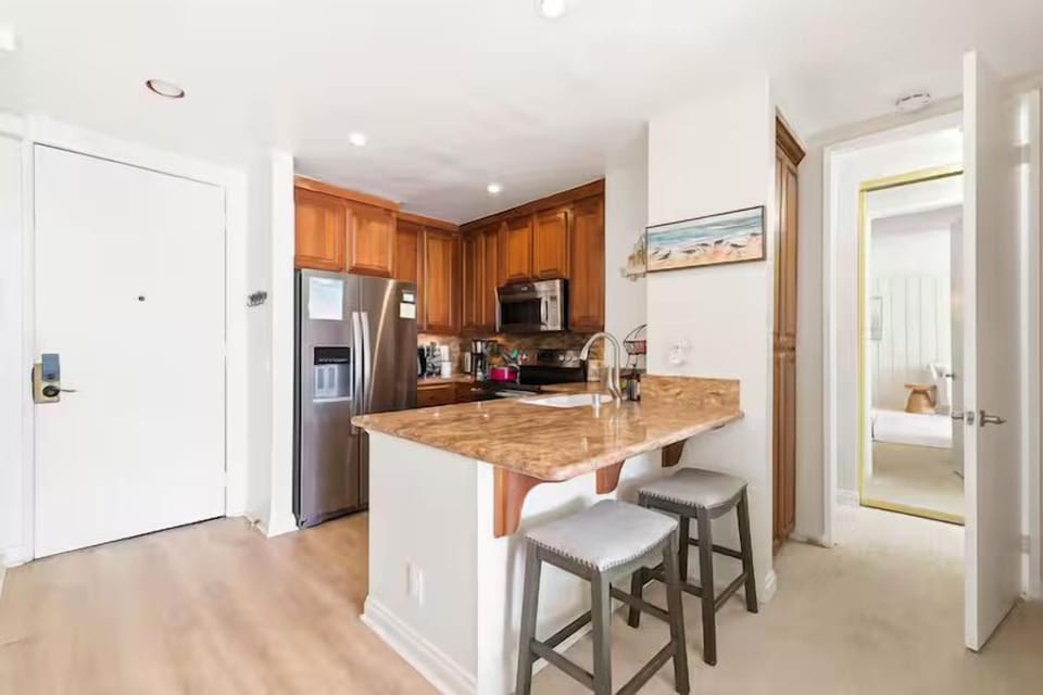 fully equipped kitchen with pots and pans, fridge, stove, oven, microwave, coffee maker, electric kettle, cooking utensils, dishes, silverware, and glasses.