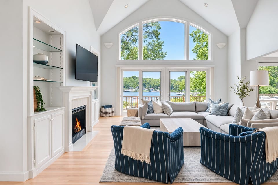 Spacious living room with fireplace, smart TV, deck access & water views.