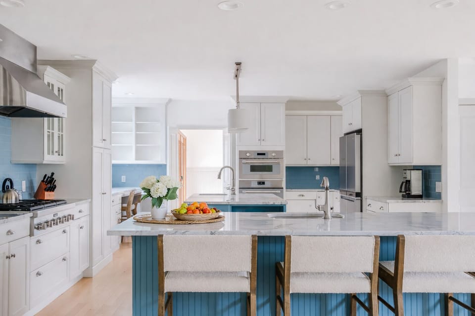 Modern chef’s kitchen with island seating, stainless appliances & full cookware.
