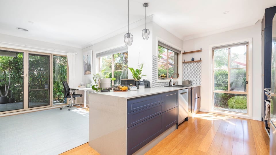 Open-plan kitchen and dining framed by lush greenery.