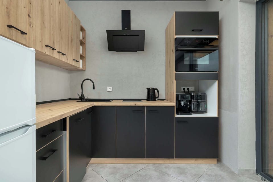 A compact kitchen corner with wooden cabinets, a stovetop, and a sink. The design emphasizes simplicity and usability.