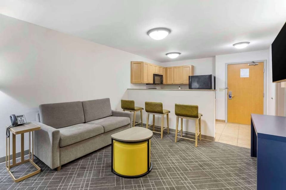 Open living space with sofa, bar stools, and kitchen right behind
