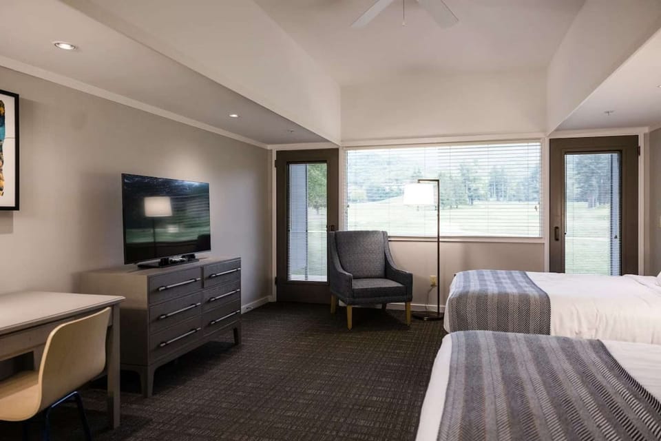 Room with TV, dresser, and two beds facing large windows