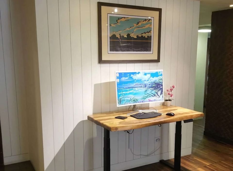 Small work desk with screen and artwork on light wood walls