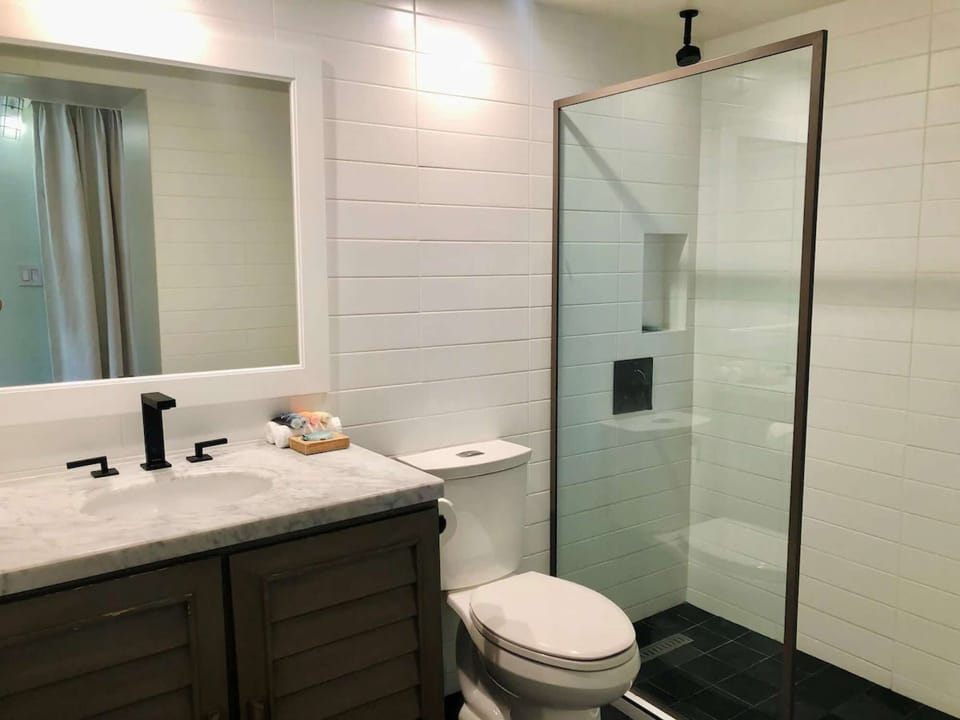 Fresh white bathroom with walk-in shower and marble counter