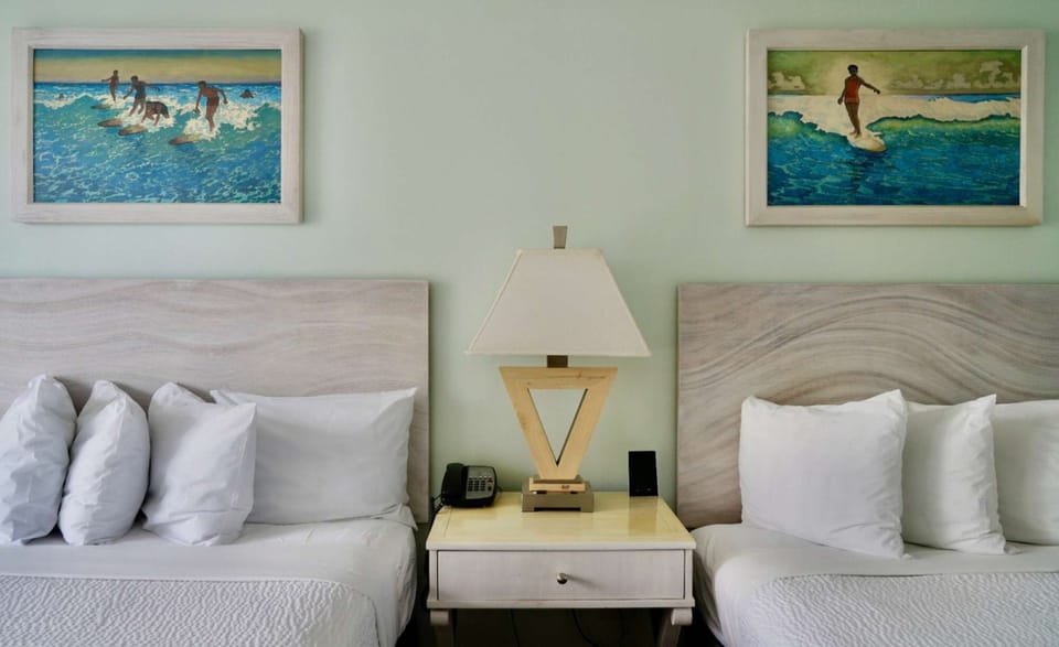 Two beds with beach artwork and lamp on nightstand