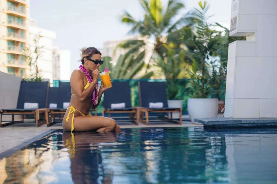 Guest sipping a cold drink while sitting by the pool edge