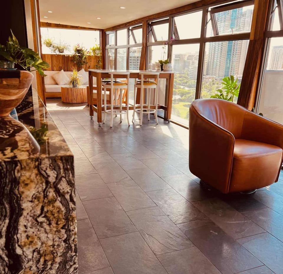 Open lounge area with tall windows, seating, and city views