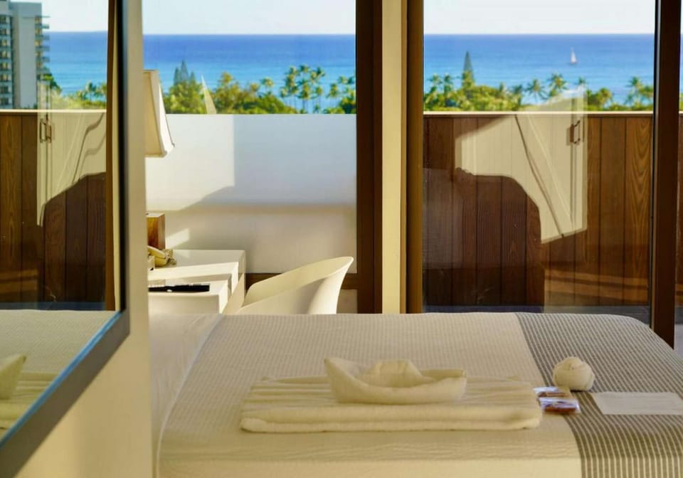 Room view showing bed and balcony facing the blue ocean