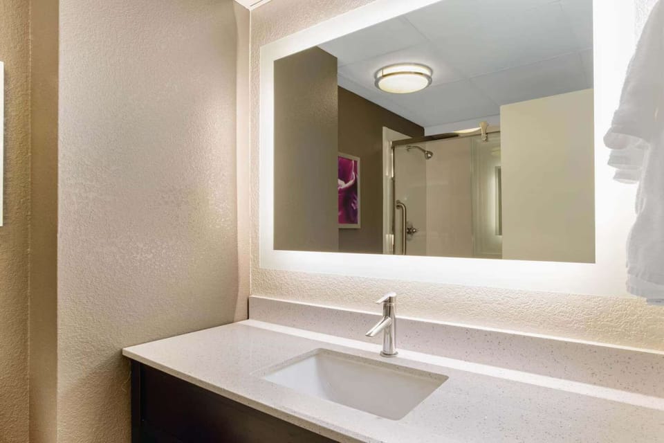 Bathroom sink with lit mirror and clean countertop space