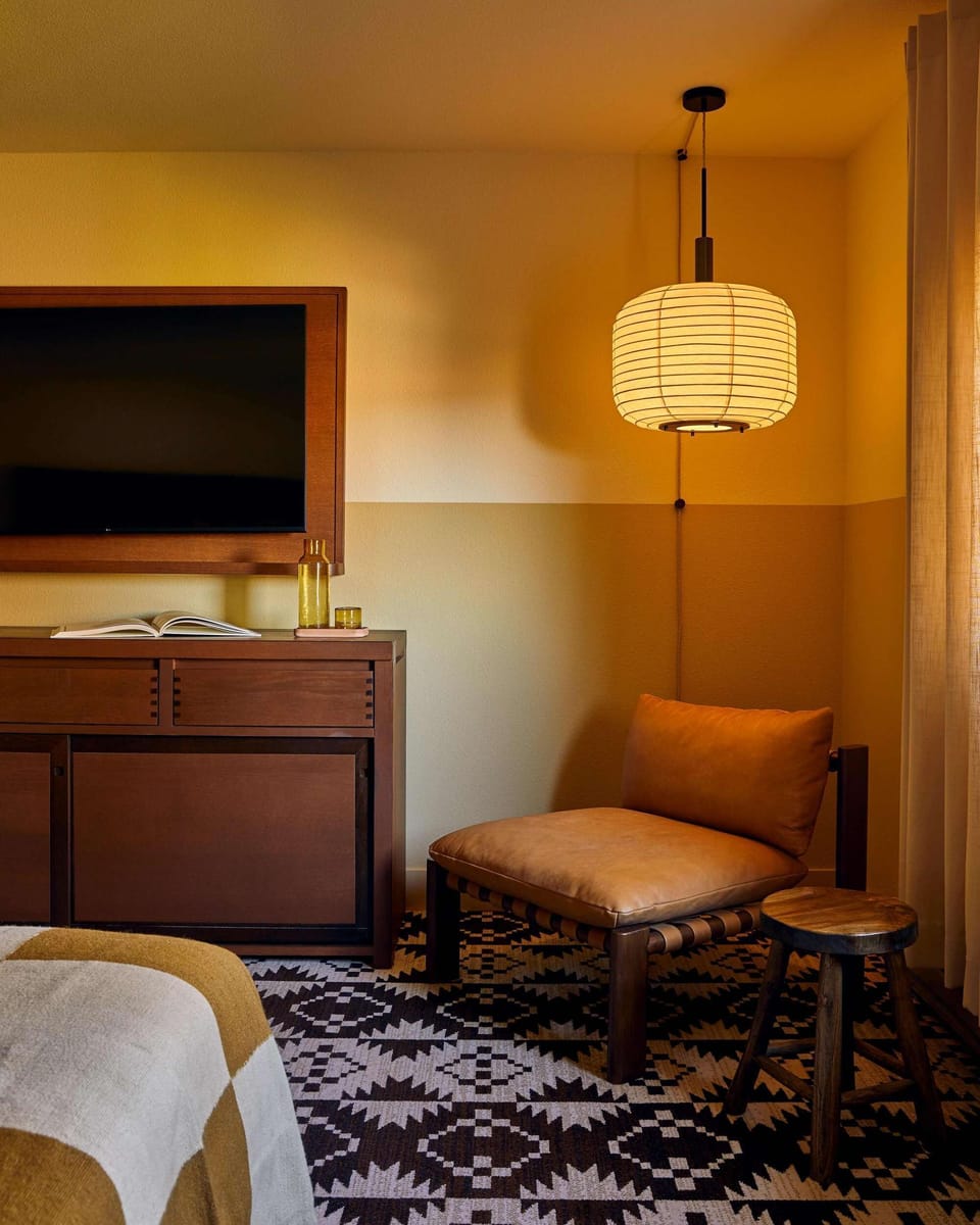 Seating corner with chair, stool, lamp, cabinet, and wall-mounted TV
