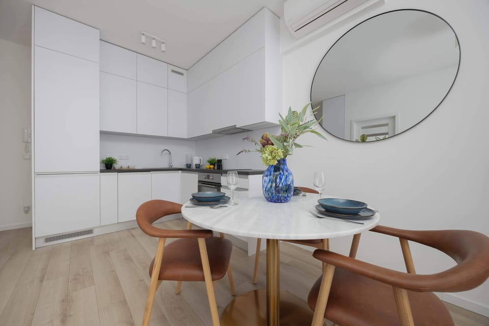 A modern kitchenette with white cabinets, an electric stove, oven, and fridge, perfect for preparing meals.