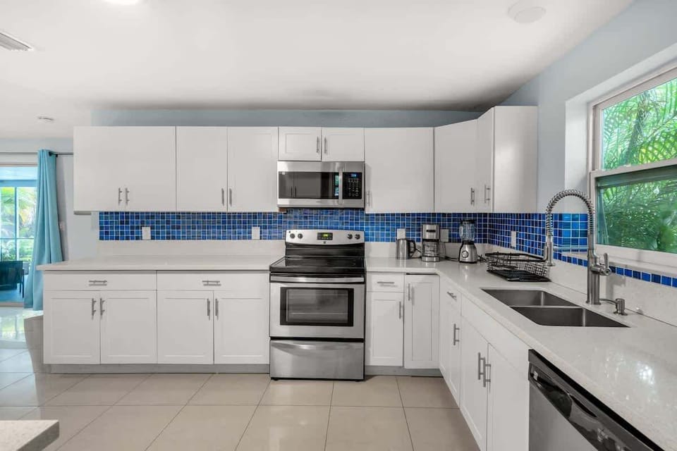 Cook in style in this modern kitchen with stainless appliances, vibrant backsplash, and natural light. A functional Airbnb space for extended stays.