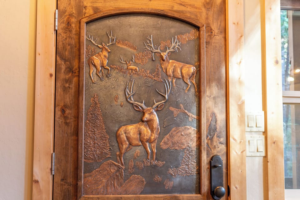 Custom carved front door with animal scenes and copper accents