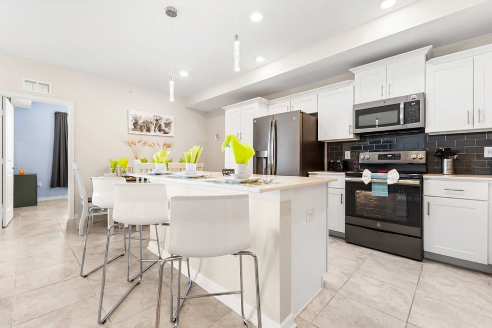 Bright, modern kitchen with pendant lighting, island breakfast bar, and stainless appliances-gather here for tasty moments.