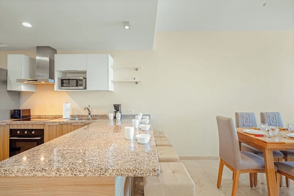 Fully equipped modern kitchen with stainless appliances and bar seating, ideal for cooking and gathering together.