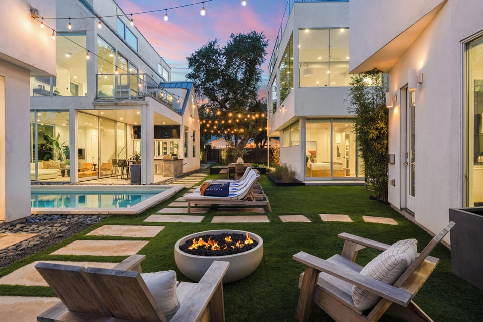 Shared outdoor retreat with a sleek pool, lounge chairs, and glowing string lights.
