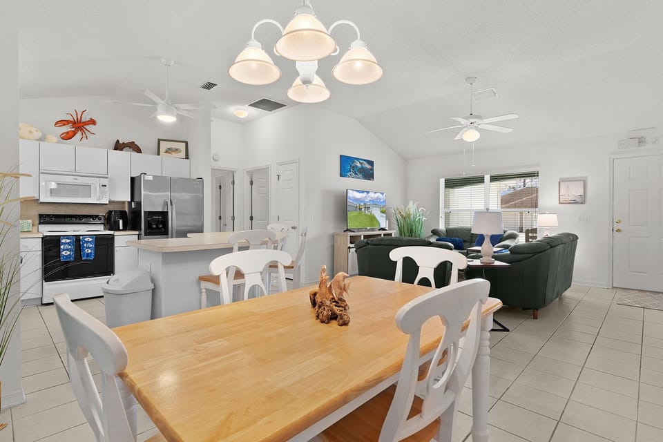 Gather around the warm wooden dining table where memories unfold, with your fully-equipped kitchen and cozy living space creating the perfect backdrop for vacation moments.
