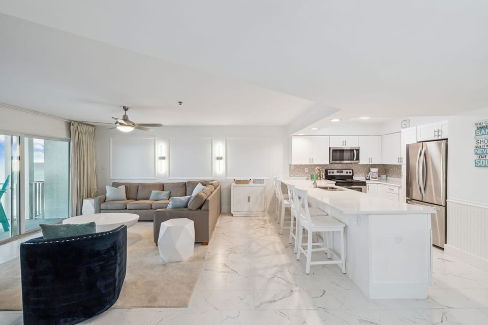 Sink into your plush sectional and enjoy the seamless flow between your modern kitchen and living space, where marble floors gleam under natural light.