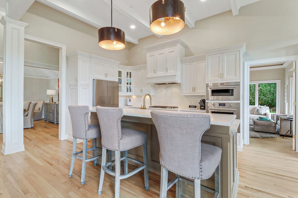 Crisp white cabinetry with custom millwork, quartz countertops, and a statement range hood create a clean, elevated look.