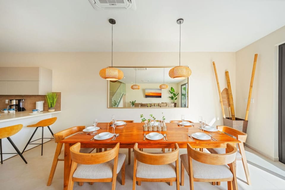 Elegant open-plan dining area with wood table and warm pendant lighting.
