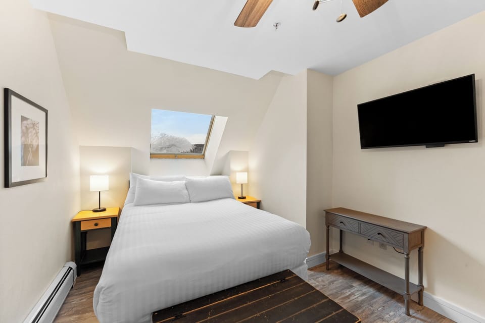 Drift off beneath the skylight's natural glow in your peaceful bedroom retreat with mountain views.