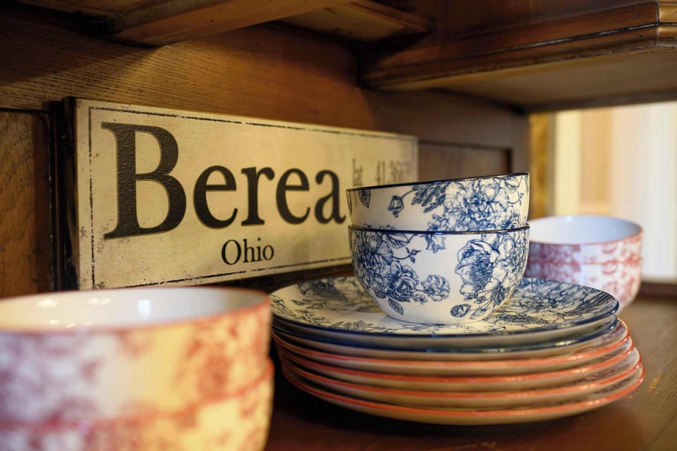 Charming shelf display featuring patterned dishware and a decorative Berea, Ohio sign.