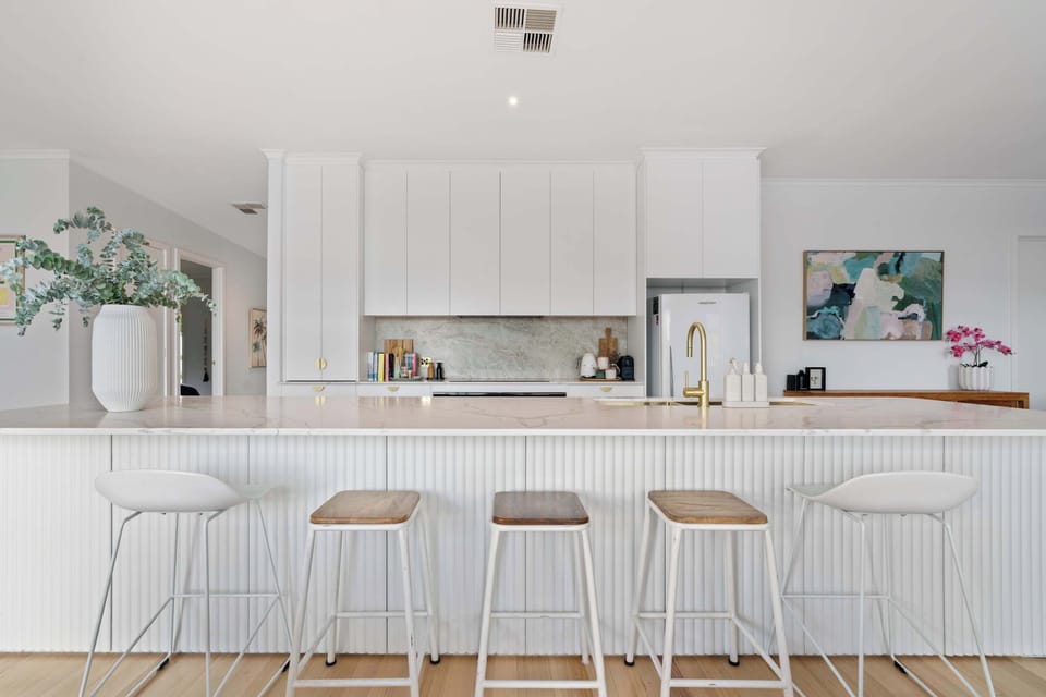 A beautifully appointed entertainer’s kitchen with immense Calacatta Combo stone island