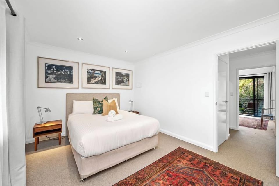 Escape to this bright and minimalist bedroom featuring a comfortable queen-sized bed and stylish decor. Enjoy the subtle warmth from the patterned rug and easy access to a private balcony, perfect for your morning coffee.