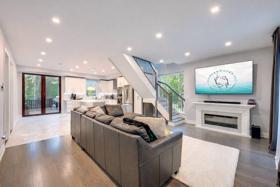 Bright open-plan living with fireplace, big TV, and sleek chef’s kitchen