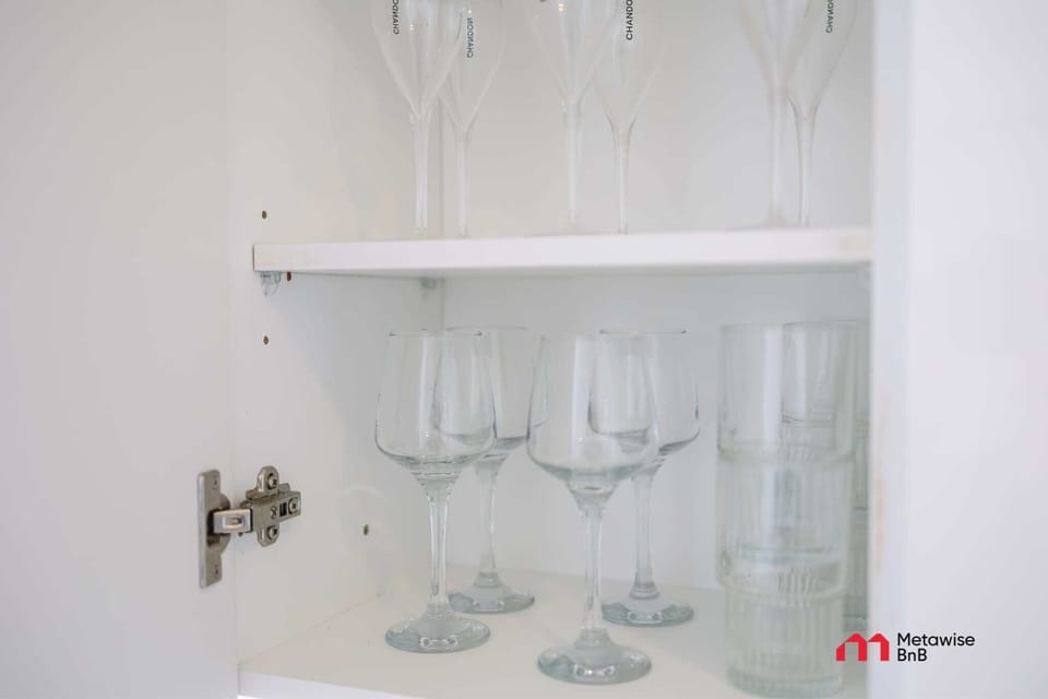 Glassware neatly arranged in kitchen cabinet.