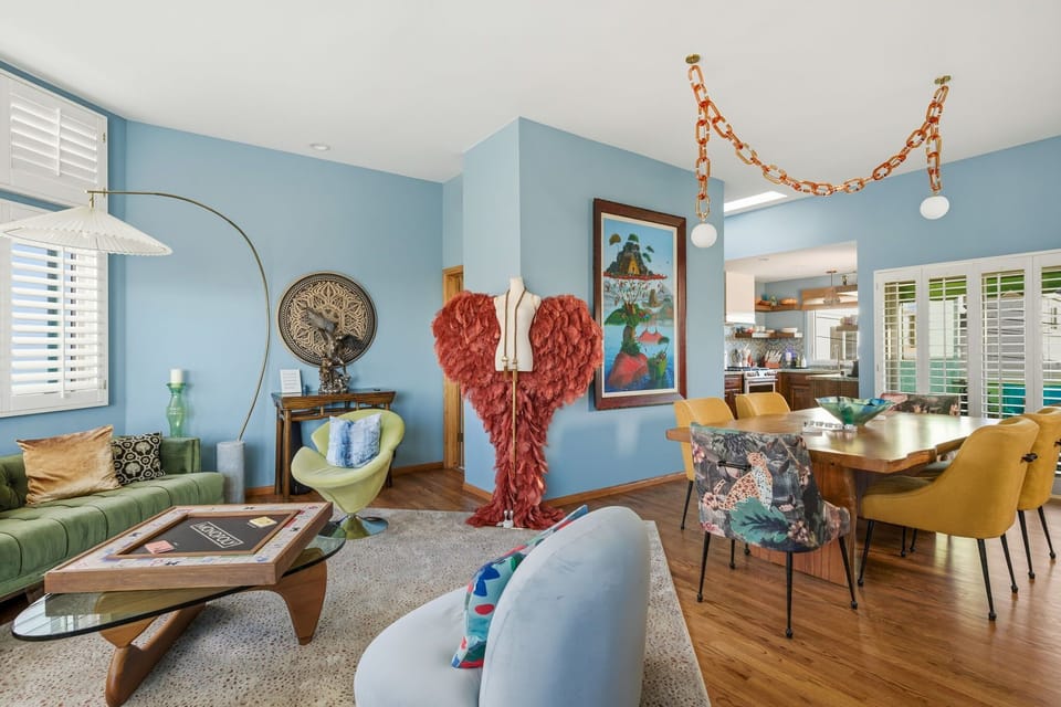 A vibrant living and dining space filled with curated art, playful colors, and cozy seating for relaxed gatherings.