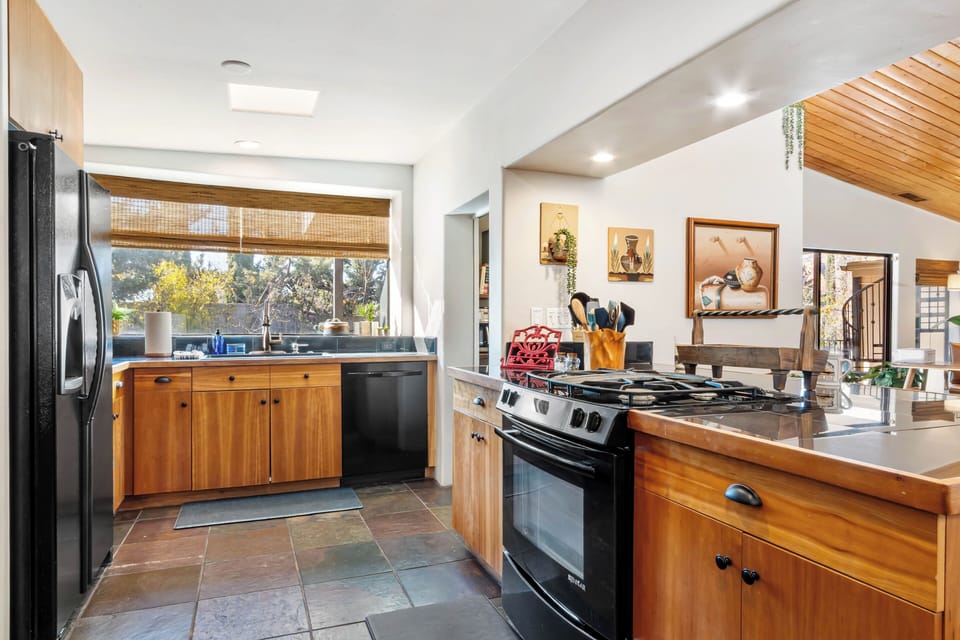 Light-filled kitchen with granite tile counters, stainless steel appliances, gas burner and a large picture window