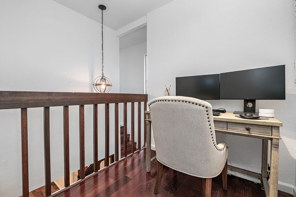 A comfortable desk setup in the primary bedroom offers a functional space to work while enjoying coastal living
                